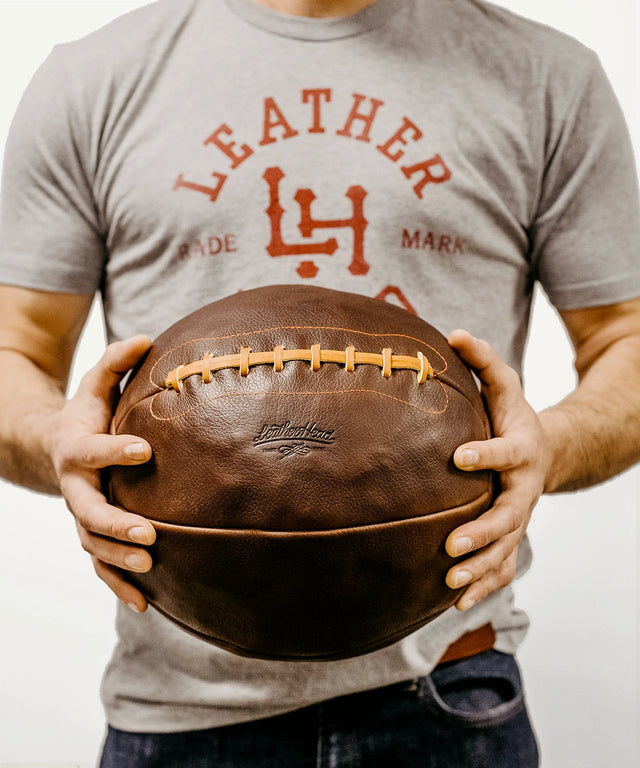 Man holding a 14lb leather medicine ball from Leather Head Sports with stitched details