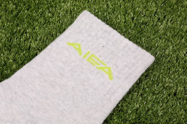 Close-up of AIEA Golf sock in light gray showcasing fashionable womens golf clothing on green grass