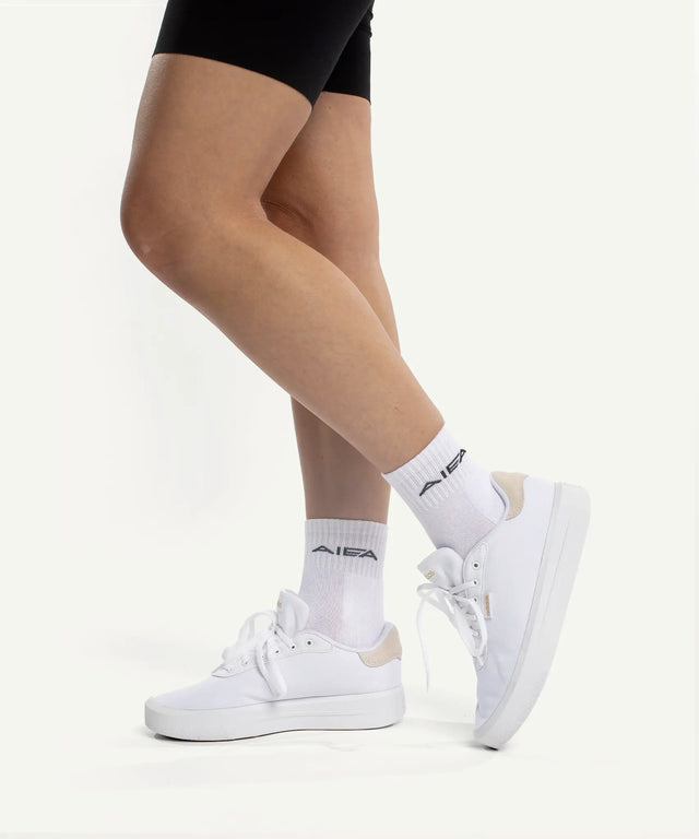 Woman wearing AIEA Golf white sneakers and branded socks showcasing fashionable womens golf clothing style