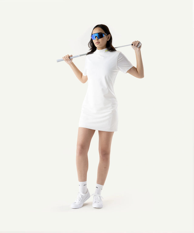 Woman wearing AIEA Golf white dress and sunglasses holding golf club in fashionable womens golf clothing