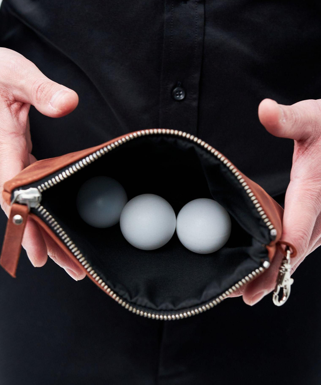 Pikore golf field pouch in brown leather with zipper, holding three white golf balls inside