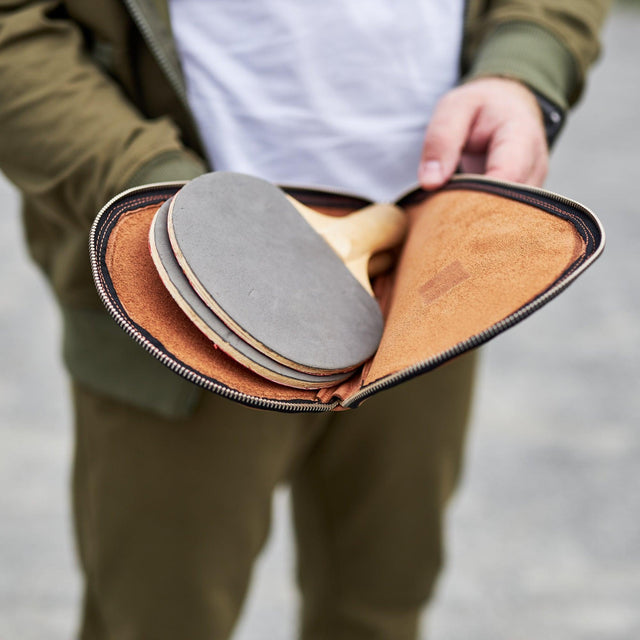 Leather ping pong paddle case by Pikore open showing two paddles inside held by a person