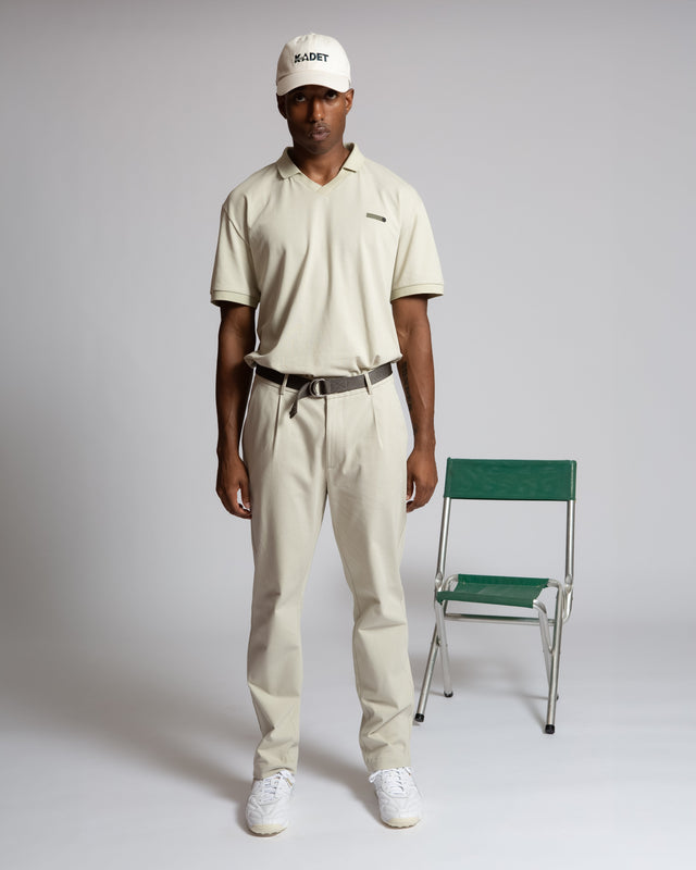 Kadet men's performance polo shirt in beige worn with matching pants and white cap