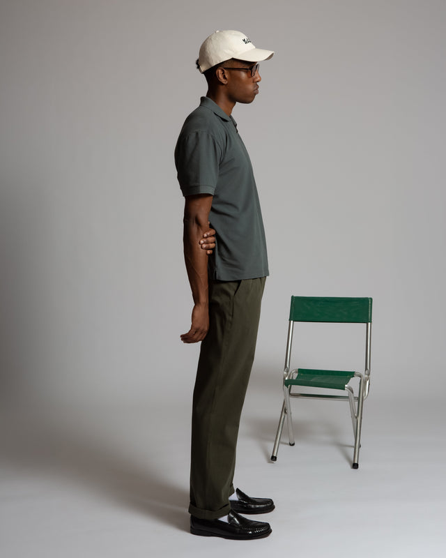 Kadet men's performance polo shirt worn by model in dark green paired with olive pants and white cap