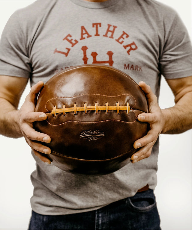 Person holding a 14 lb Chromexcel medicine ball made of brown leather by Leather Head Sports
