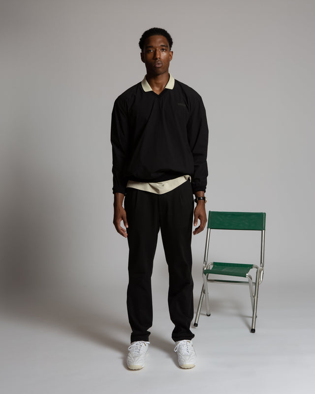 Model wearing black Kadet Fabien windbreaker jacket paired with black pants and white sneakers