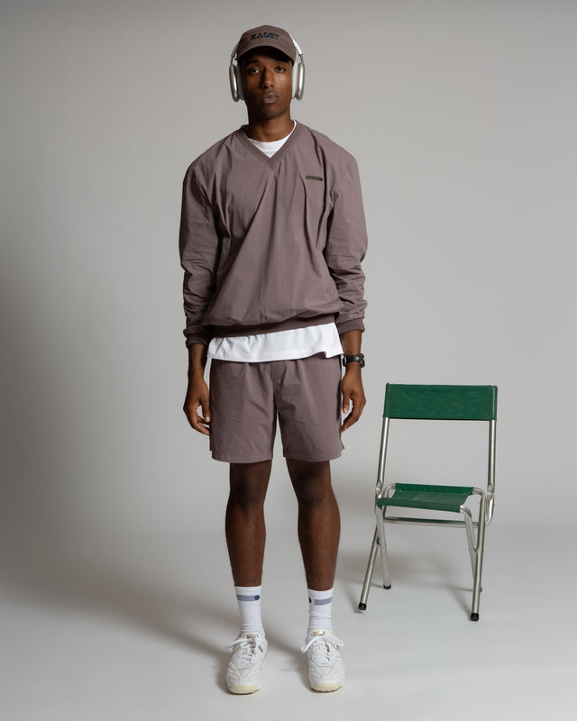 Kadet Fabien windbreaker jacket in muted brown worn by male model with matching shorts and cap