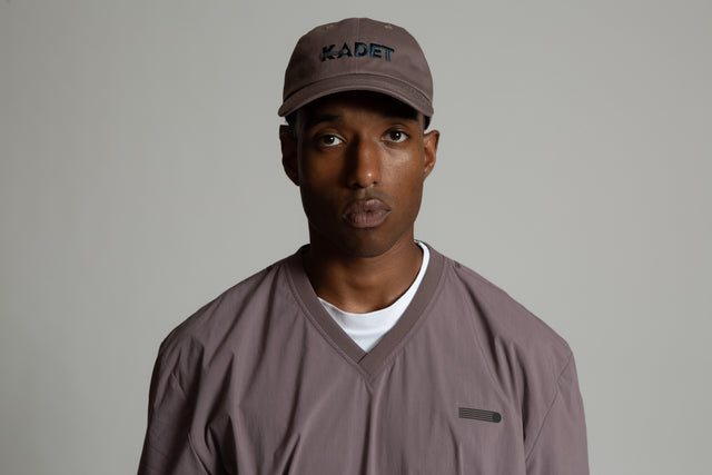 Kadet Fabien windbreaker jacket in muted brown worn by model with matching Kadet cap
