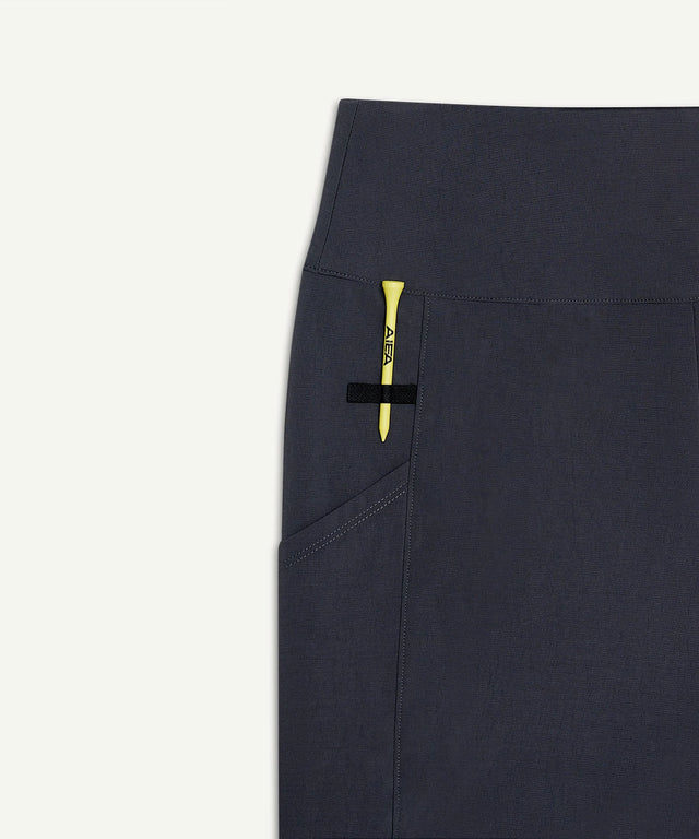 Close-up of AIEA Golf black skirt pocket with yellow tee showcasing fashionable womens golf clothing