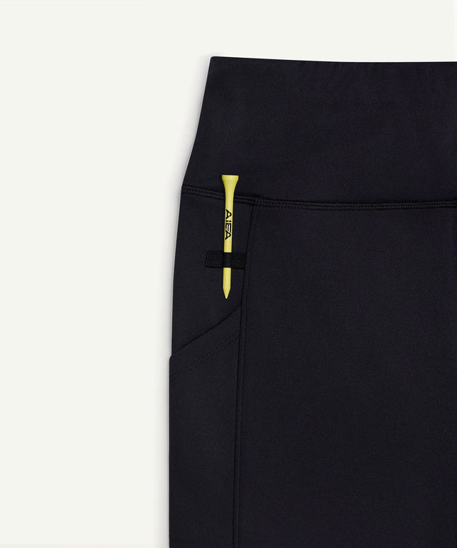 AIEA Golf black skirt with a pocket holding a yellow tee showcasing fashionable womens golf clothing