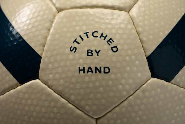 Close-up of Hayworth Athletic standard model soccer ball with stitched by hand text on beige and black panels