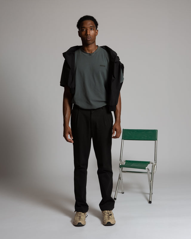 Male model wearing Kadet Henrik pique tee for men in dark gray with black pants and beige sneakers