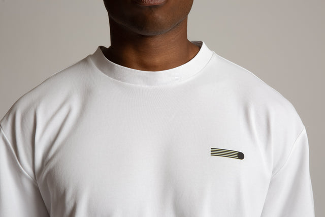 Close-up of a man wearing a white Henrik pique tee for men by Kadet with minimalist chest logo
