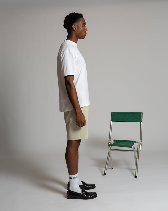 Side view of man wearing white Henrik pique tee for men paired with beige shorts and black shoes