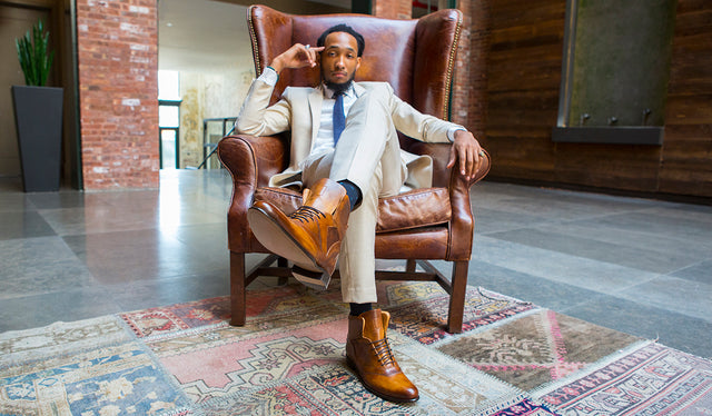 Man wearing Italian made mens dress shoe in tan leather sitting on a brown leather armchair