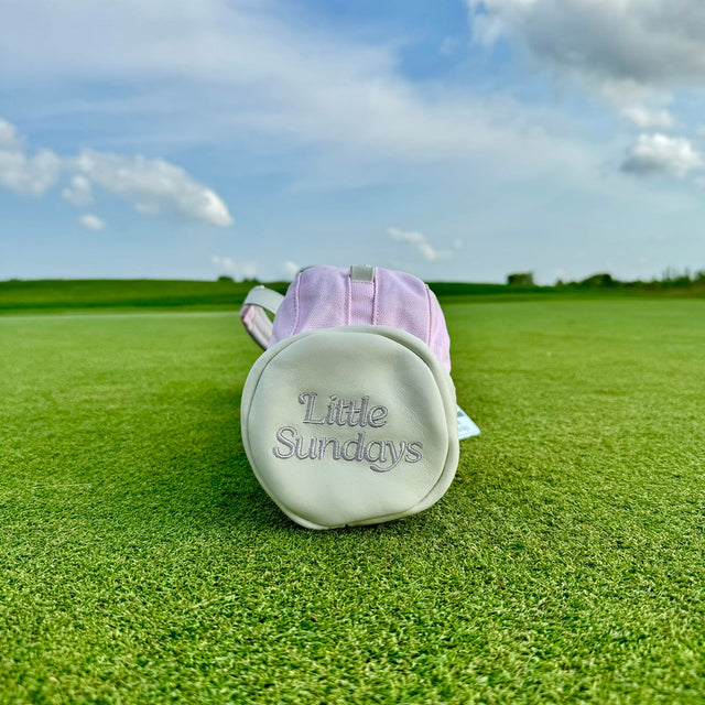 Little Sundays kids golf bag in pink with kids golf clubs on green golf course