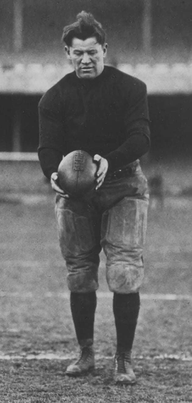 Vintage black and white photo of a football player holding leather watermelon football on field