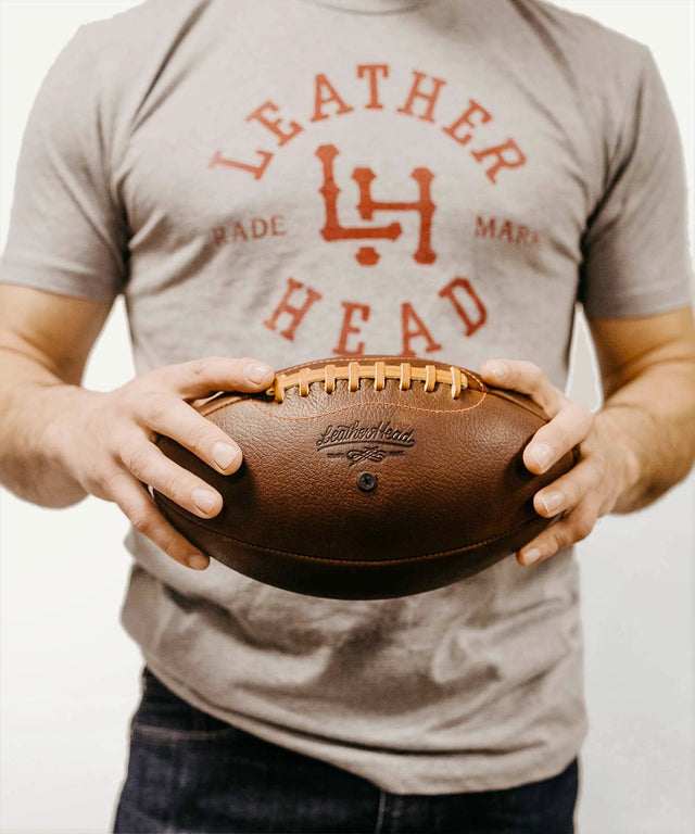 Leather Head Sports premium leather football held by person wearing Leather Head logo t-shirt