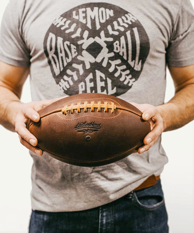 Leather Head Sports premium leather football held by person wearing gray baseball t-shirt