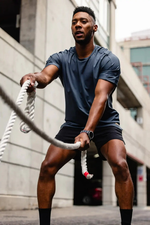 Man wearing Solstice Athletics premium workout clothing using battle ropes outdoors