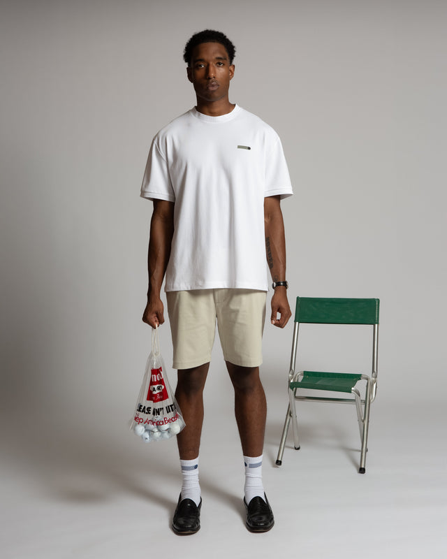 Man wearing Kadet men's chino shorts in beige paired with a white t-shirt and black shoes
