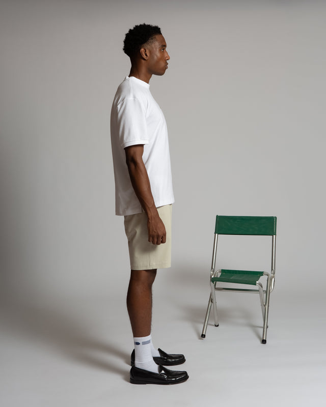 Side view of man wearing Kadet men's chino shorts in beige with white shirt and black loafers