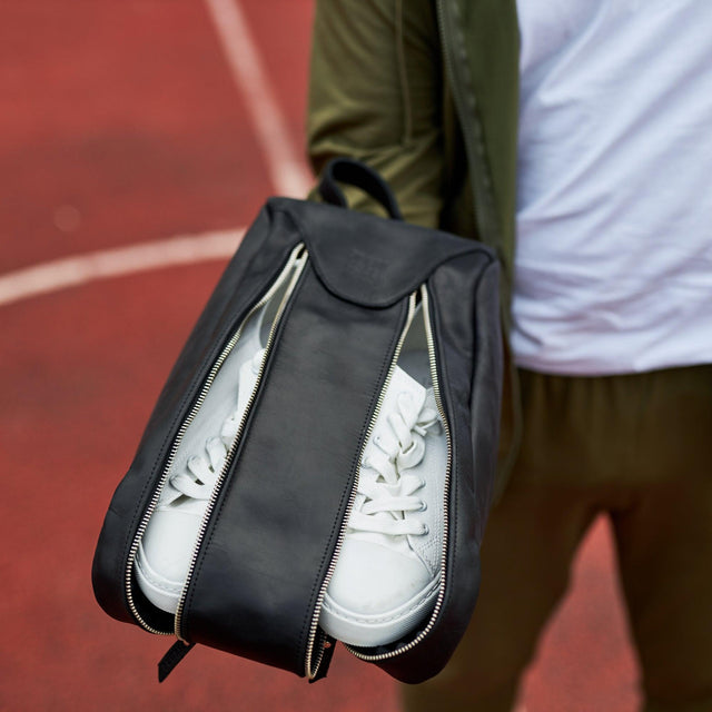 Pikore black leather golf shoe bag holding white sneakers with dual zipper compartments