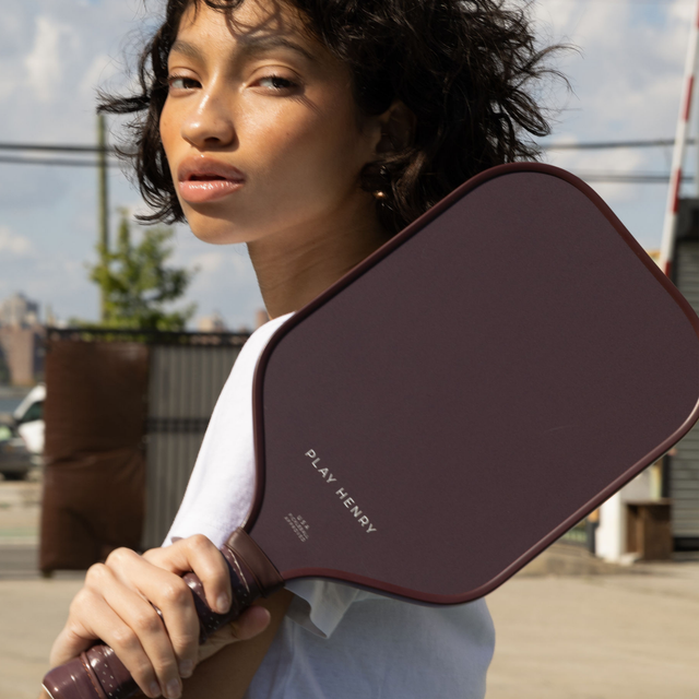 Play Henry carbon fiber pickleball paddle held by woman outdoors with urban background