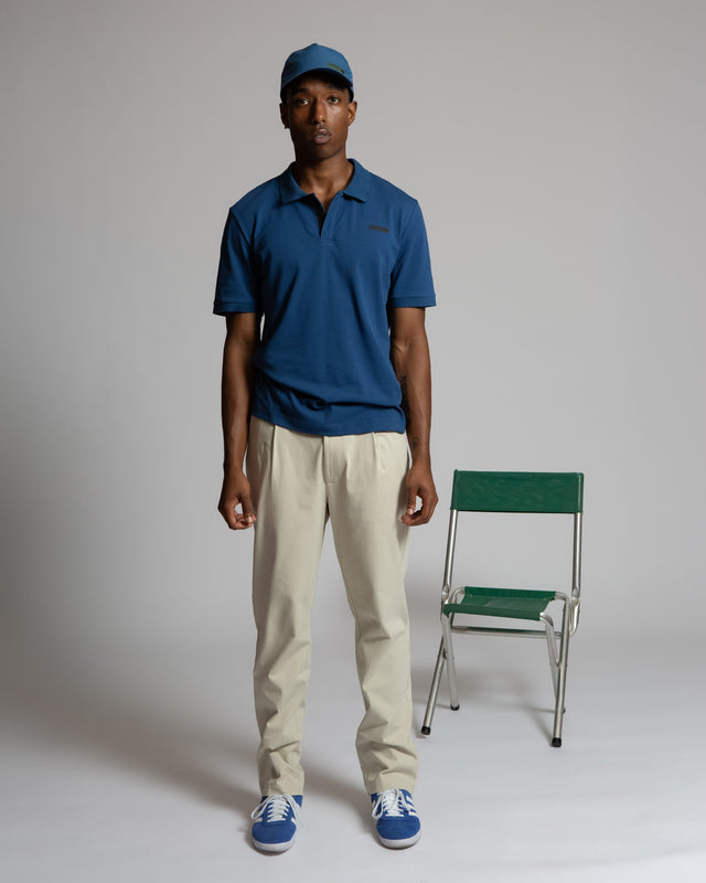 Kadet pleated chino pants for men in beige worn with blue polo shirt and cap