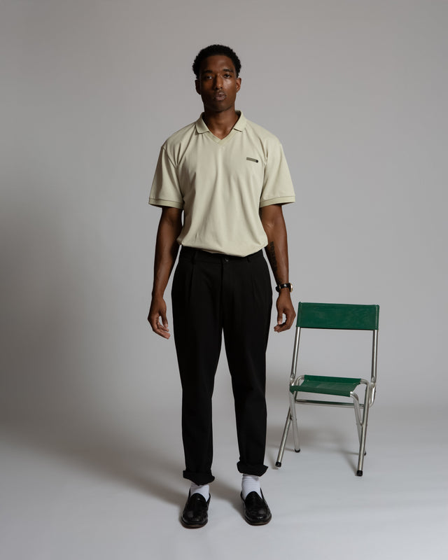 Man wearing Kadet pleated chino pants for men in black paired with beige polo shirt and black shoes
