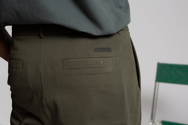 Kadet olive green pleated chino pants for men showing back pocket detail and belt loops