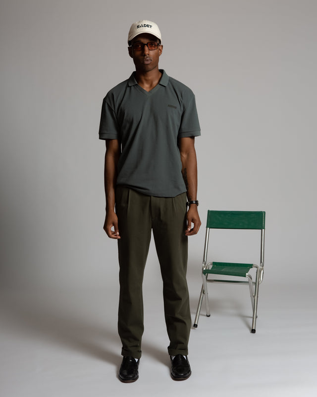 Man wearing Kadet pleated chino pants for men paired with a dark green polo and white cap