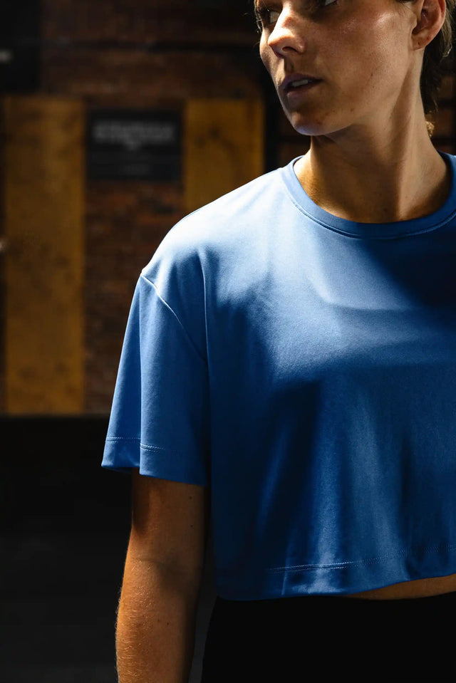 Woman wearing a blue crop top showcasing premium workout clothing by Solstice Athletics