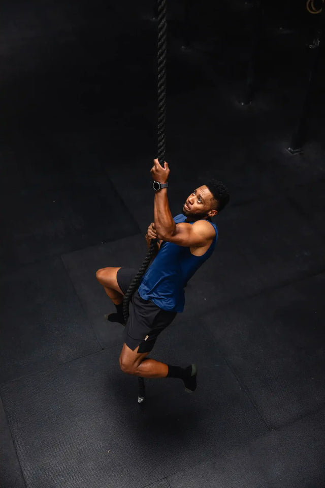Man wearing Solstice Athletics premium workout clothing climbing a rope in a gym