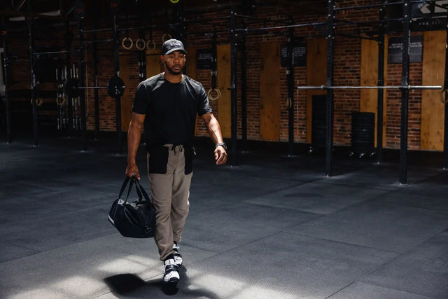 Man wearing Solstice Athletics premium workout clothing carrying a gym bag in a fitness studio