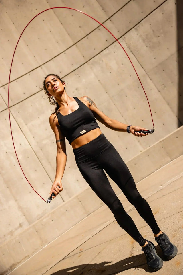 Woman jumping rope wearing Solstice Athletics black premium workout clothing set with sports bra and leggings