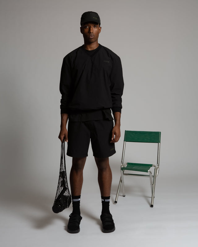 Man wearing black women's pull-on athletic shorts from Kadet styled with black long sleeve shirt and cap