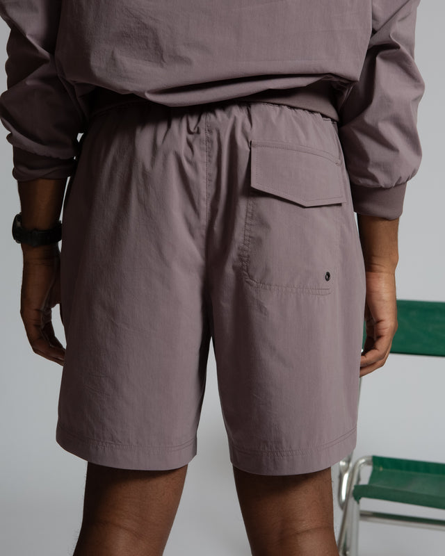 Back view of Kadet women's pull-on athletic shorts in muted purple with elastic waistband and pocket