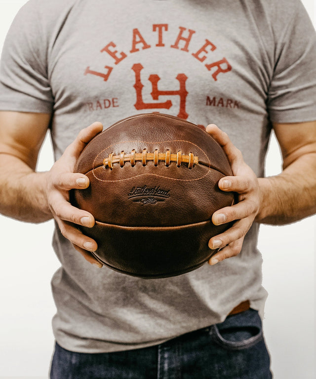 Leather Head Sports vintage leather medicine ball held by a man wearing a gray t-shirt