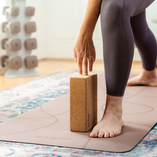 WeGym cork yoga block supporting a person stretching on a yoga mat indoors